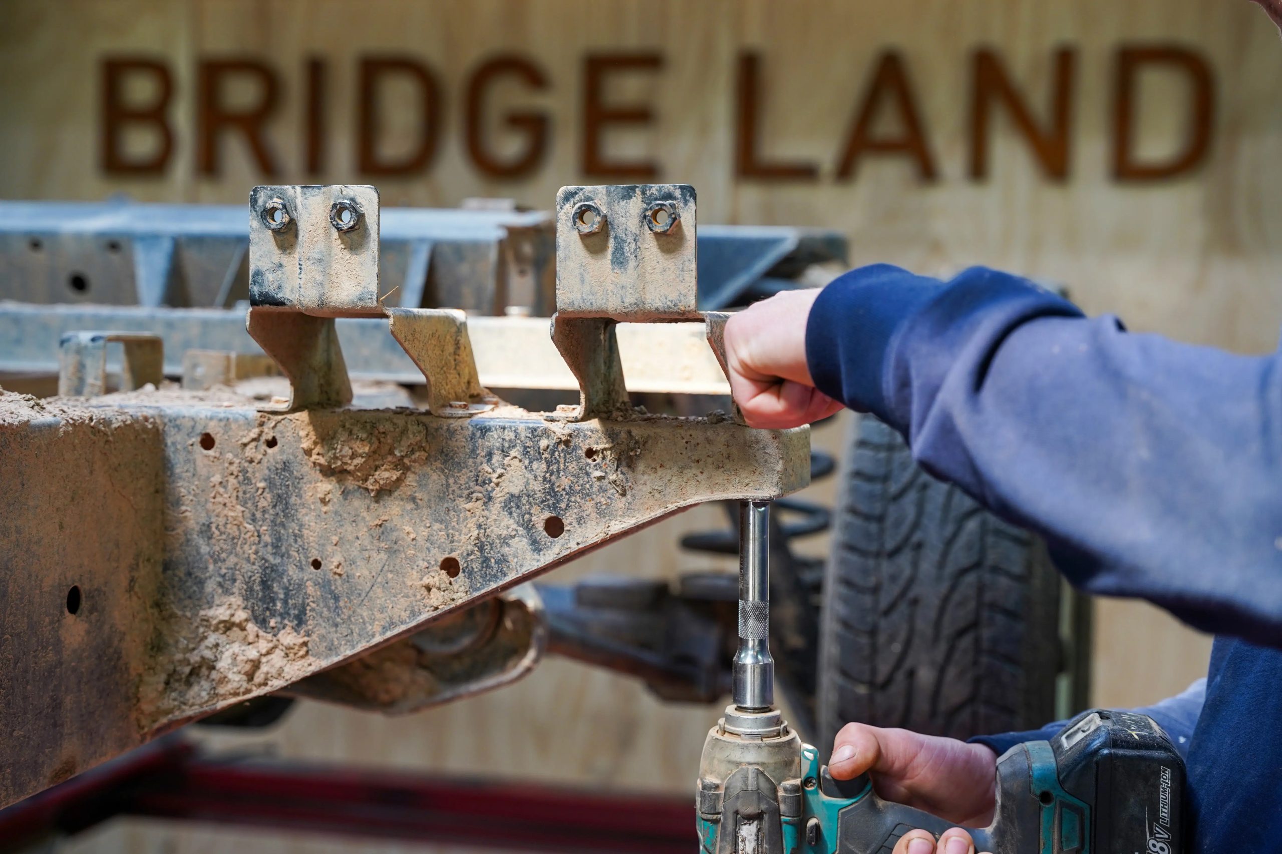 A technician's hands assessing a stripped donor Defender chassis