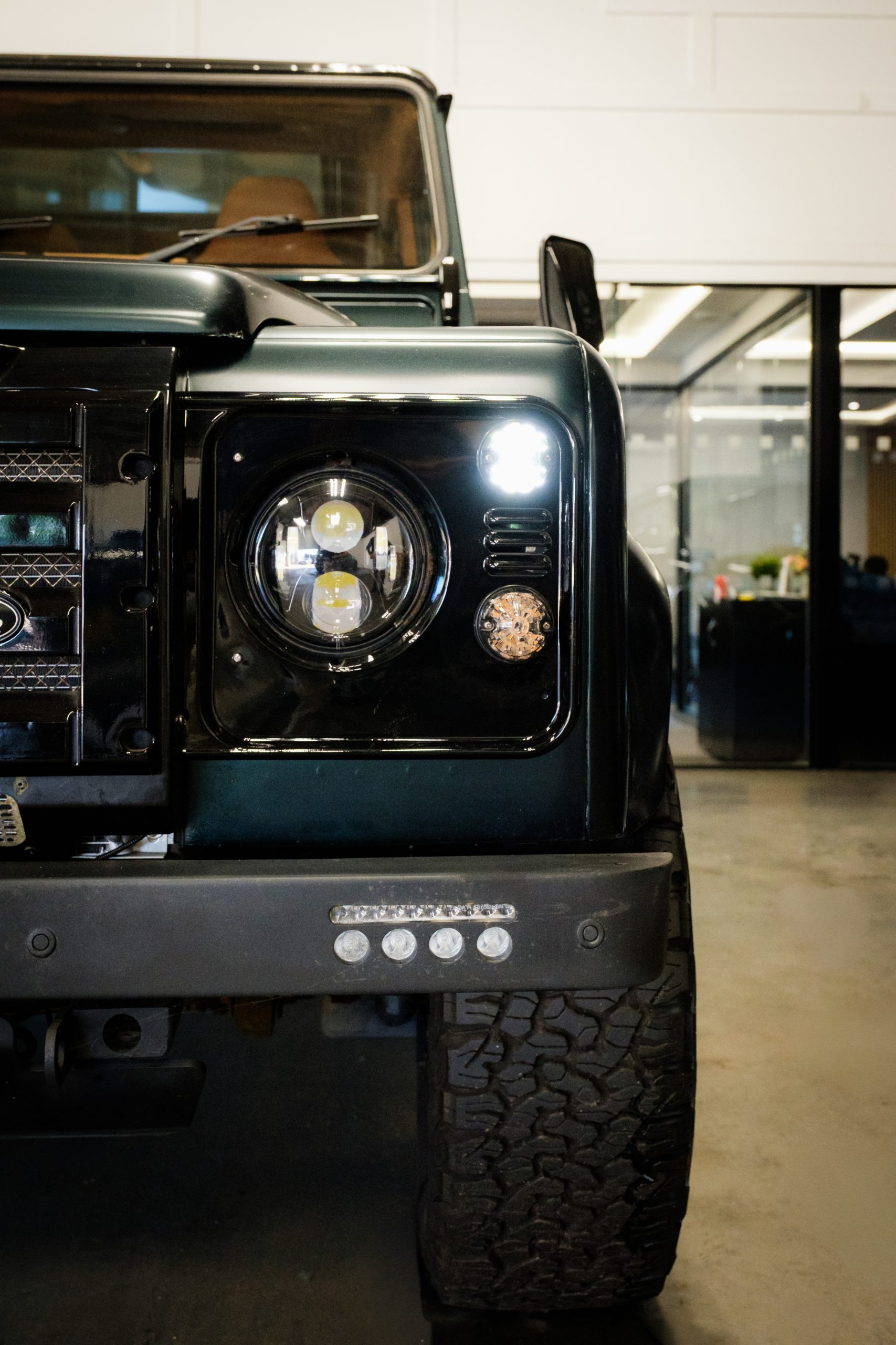 Restored Defender with an LED headlight, parked in a workshop