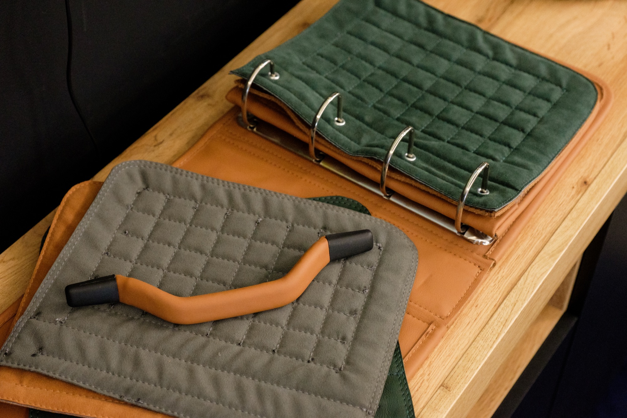 Ring-bound book of quilted leather samples beside a tan leather grip