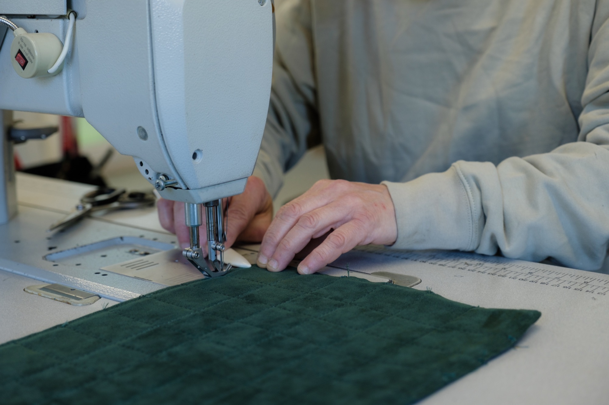 Industrial sewing machine stitching a leather panel