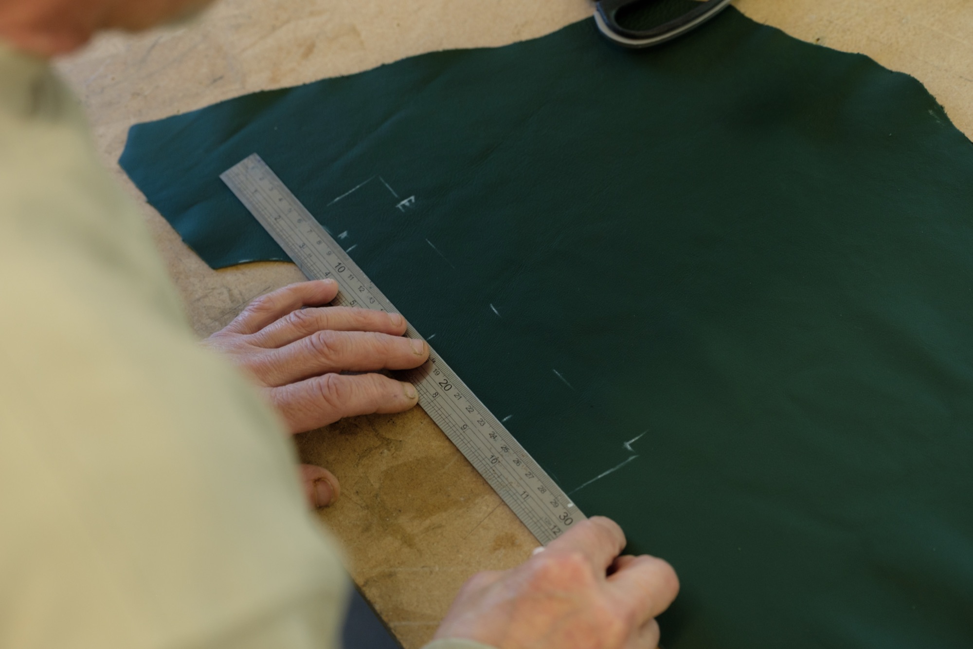 Steel ruler measuring against leather during pattern design