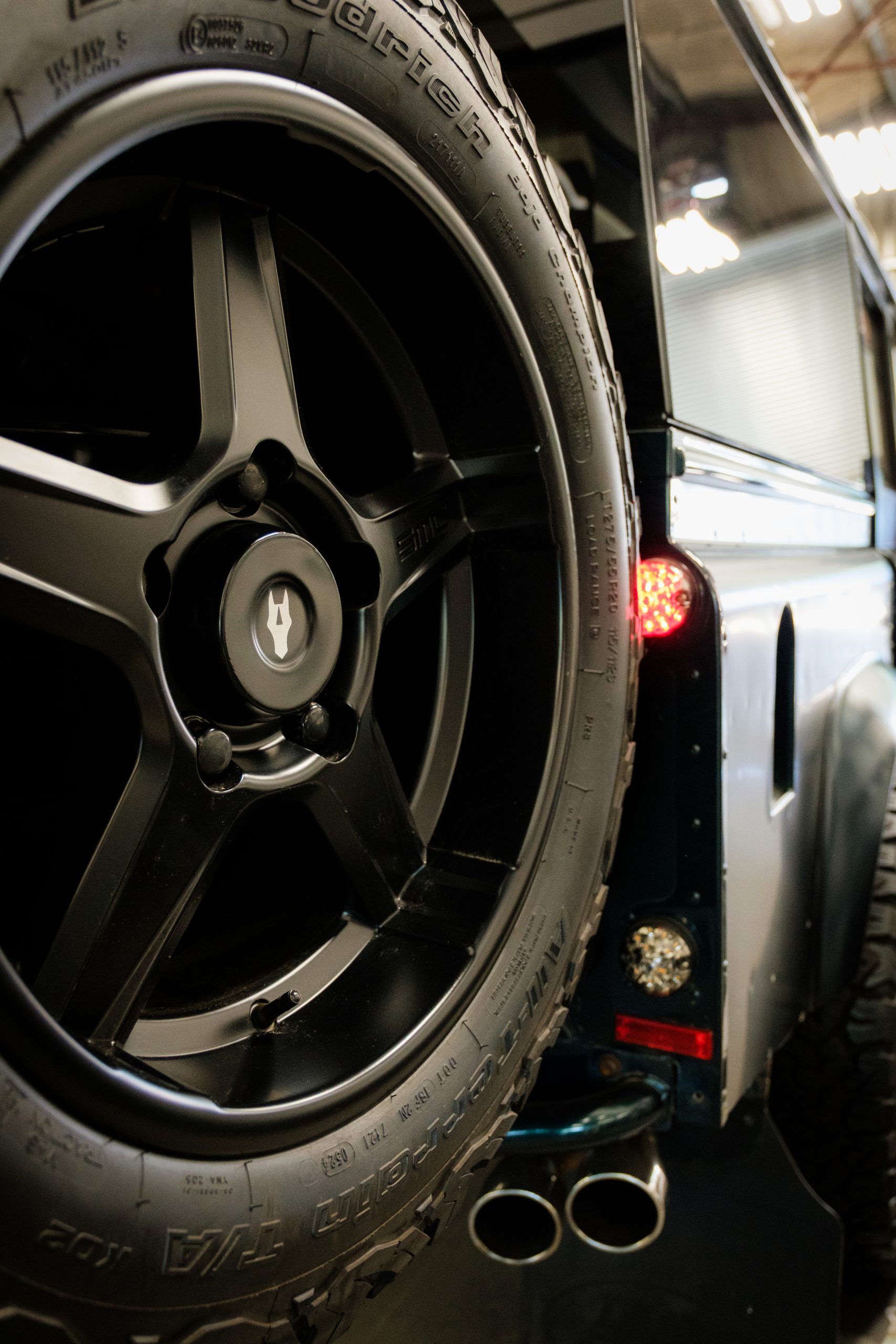 Close-up of a black alloy wheel with the Autelier crest centre cap