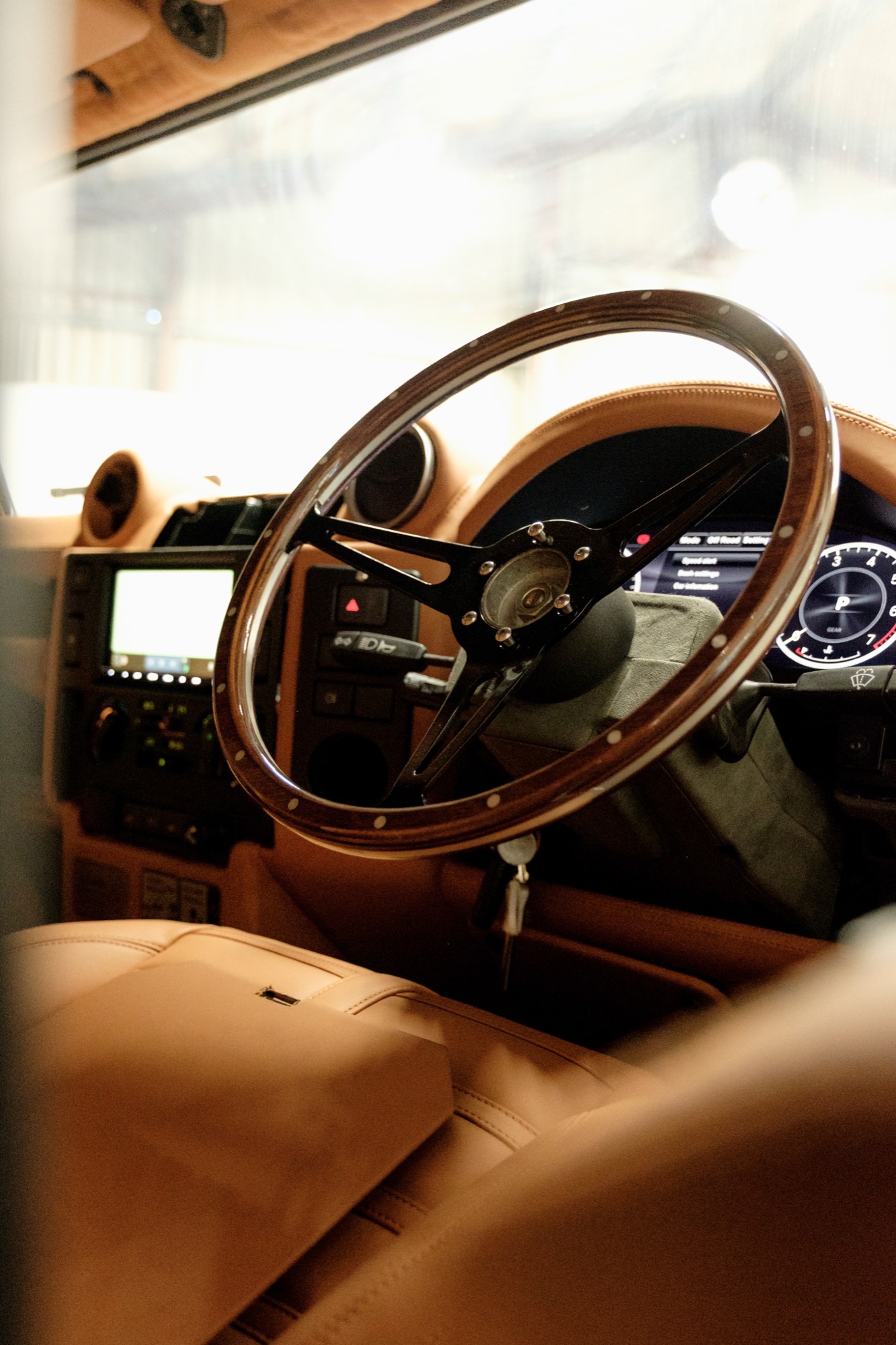 Wood-rimmed steering wheel above the tan leather cabin
